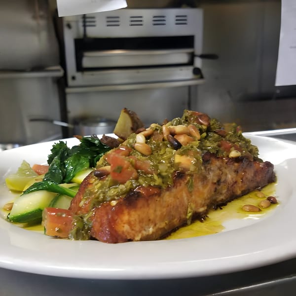 Leone's Italian salmon dish with pesto, pine nuts, diced tomatoes, zucchini, and greens.