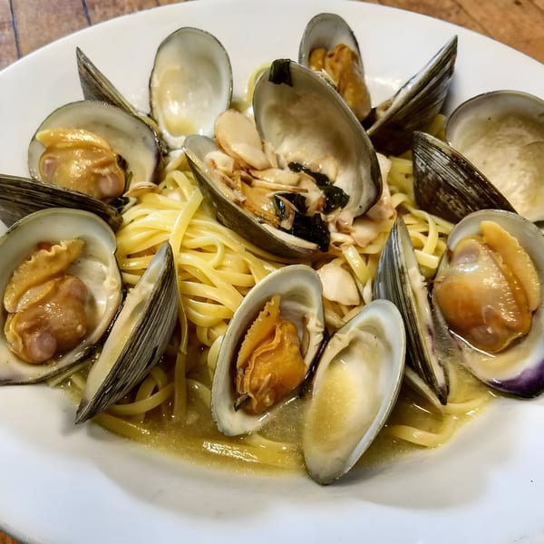 Leone's linguine with clams, featuring open clam shells and pasta in a white wine sauce.